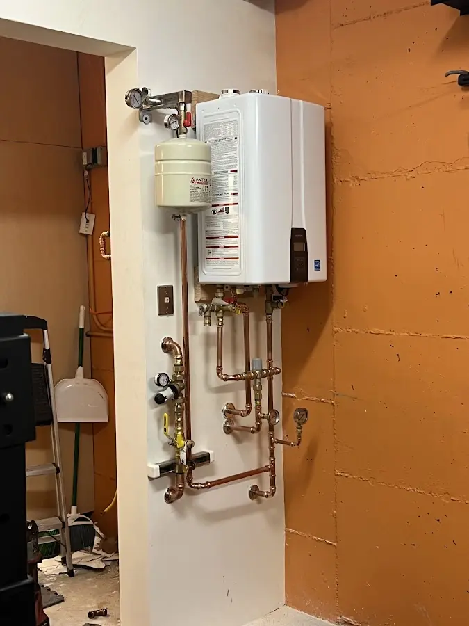 Plumbing technician inspecting water heater connections in New Milford